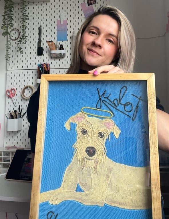Laura sosteniendo un retrato de mascota terminado